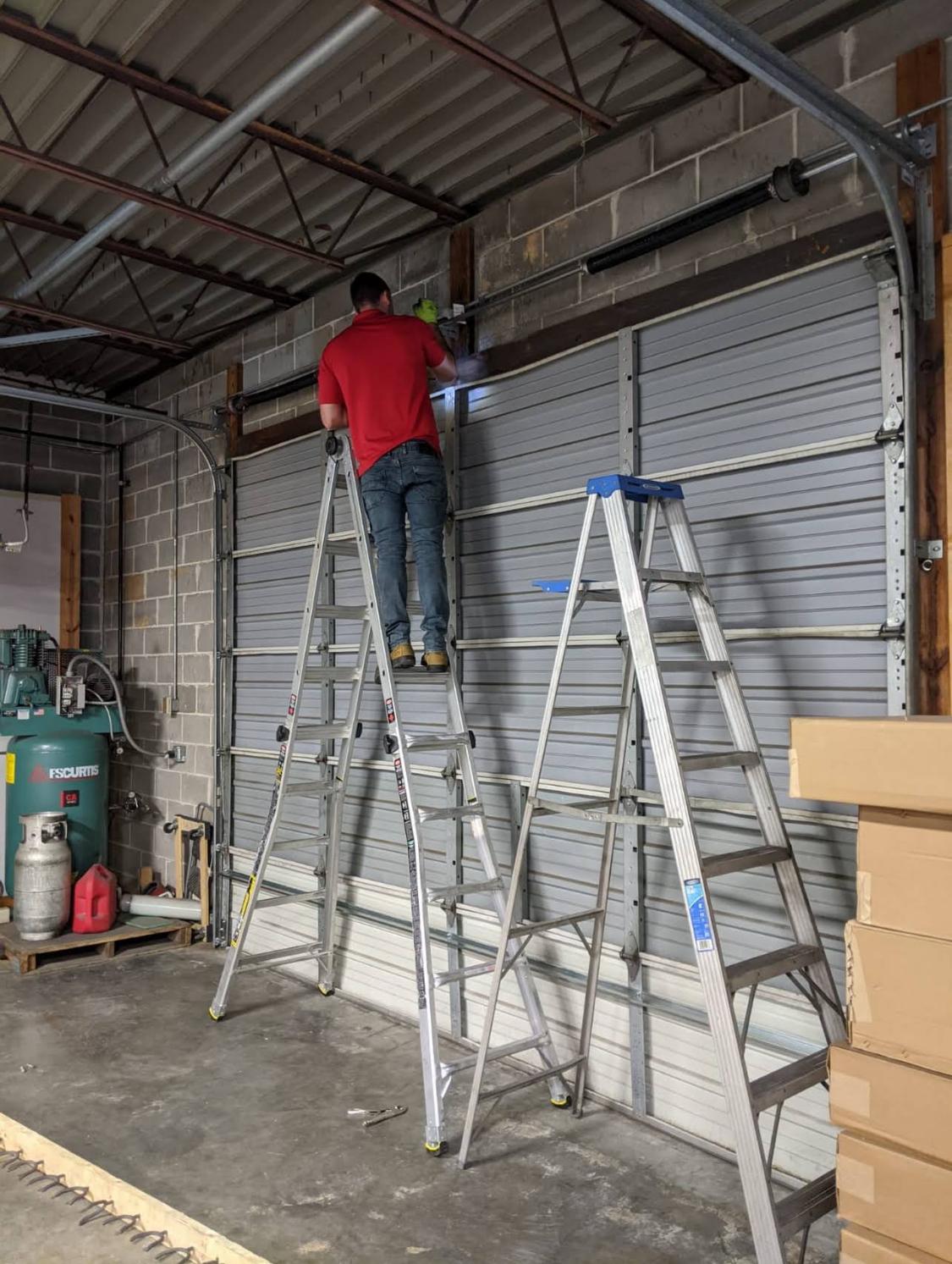 Technician on a ladder servicing a garage door