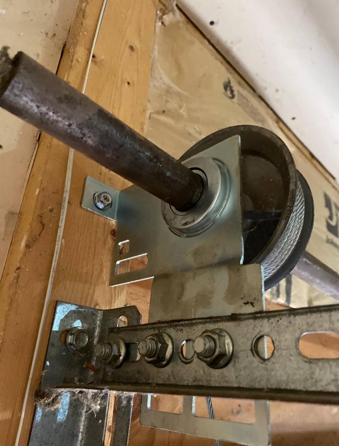 Close-up of a garage door cable pulley and bearing plate